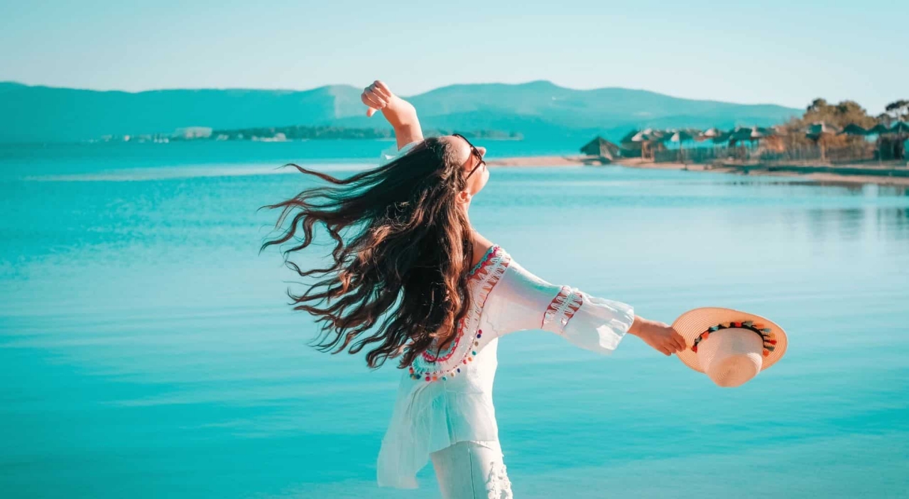happy woman on the beach turned toward the sun